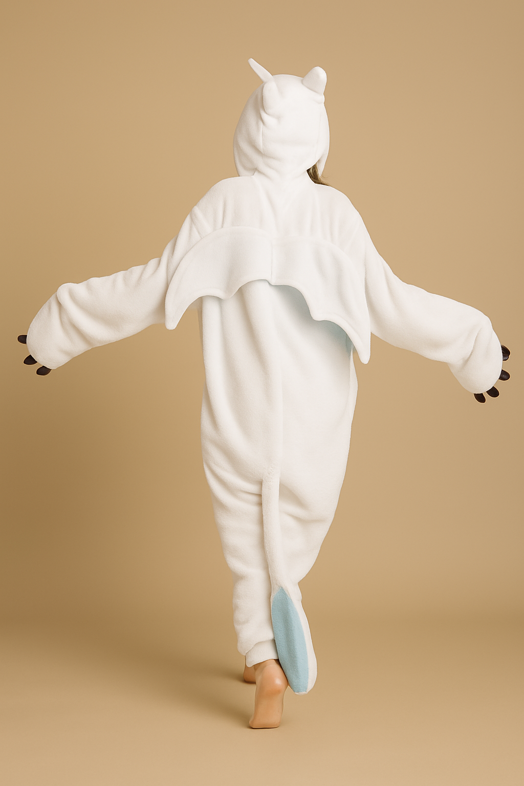 Person wearing a white unicorn onesie on a beige background